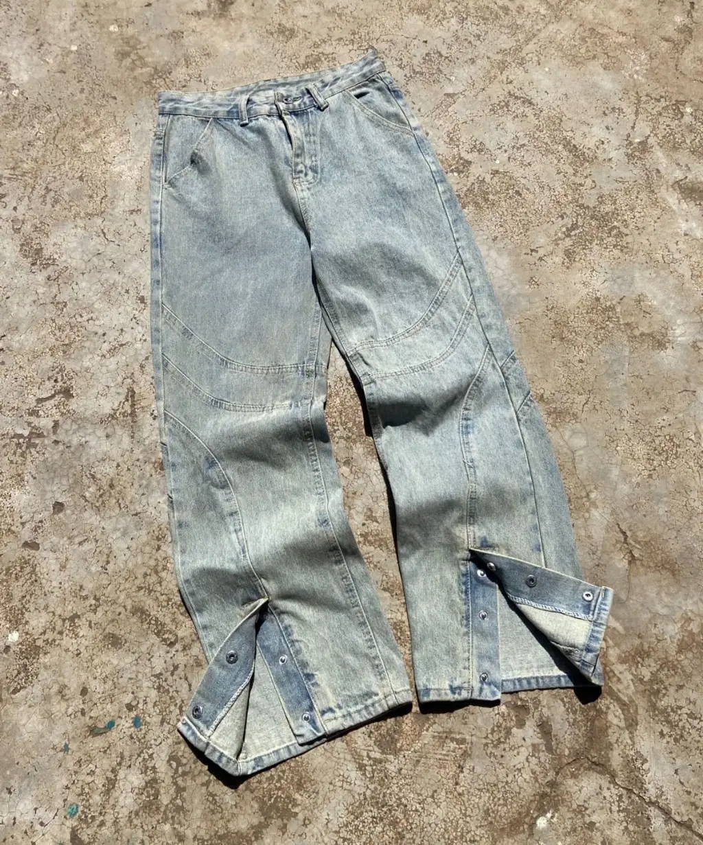 Light wash wide-leg denim jeans with panelled design and snap button hem.