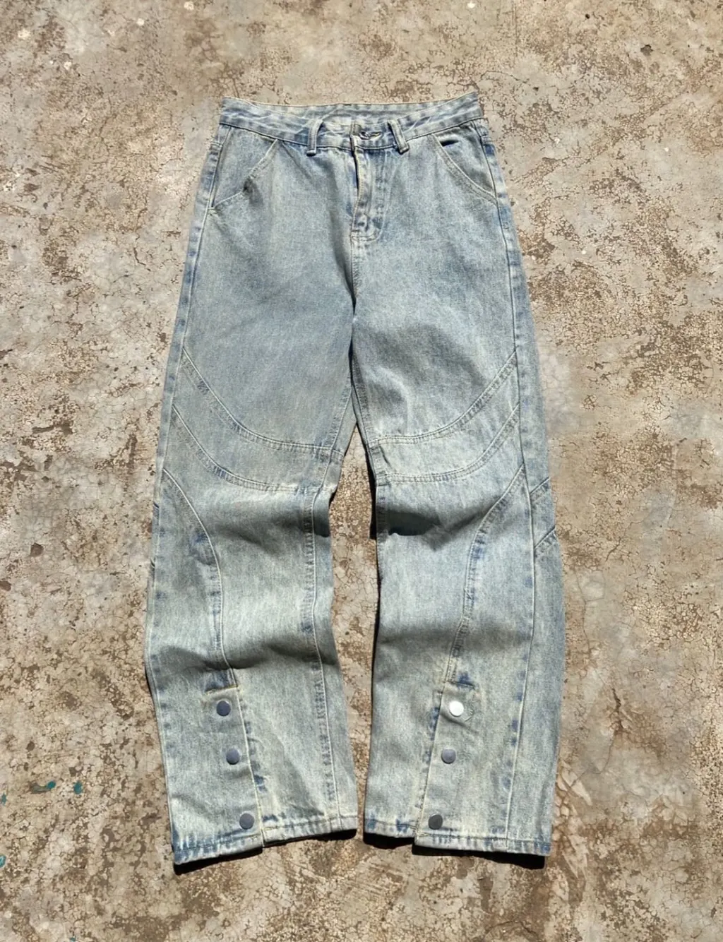 Light wash wide-leg denim jeans with panelled design and snap button hem.