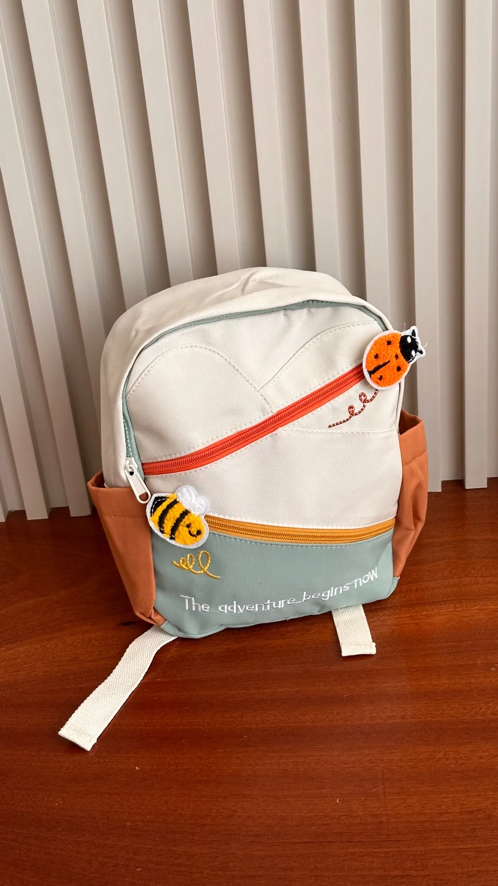 canvas backpack features an off-white, orange, and sage green color-blocking design