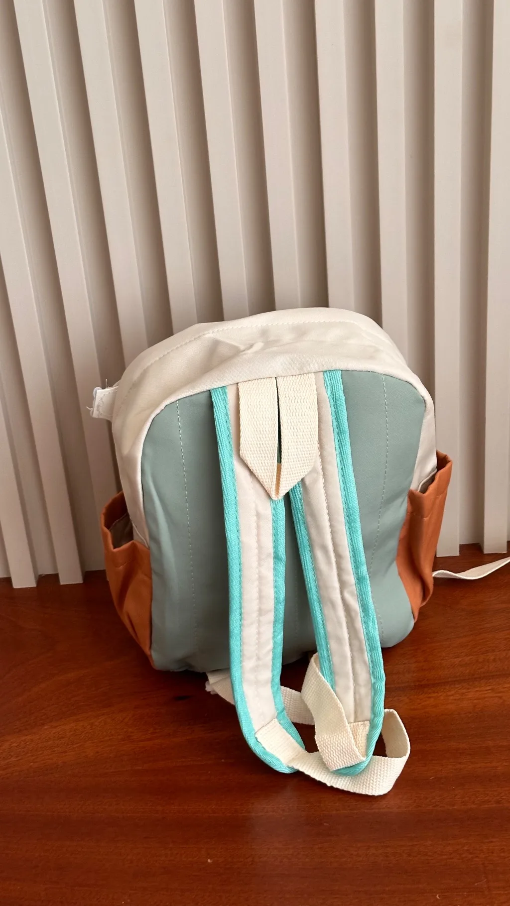 canvas backpack features an off-white, orange, and sage green color-blocking design